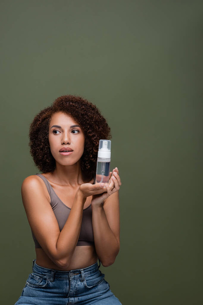 African american woman in top holding cleansing foam isolated on green  - Foto, Bild