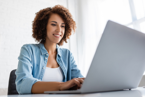 Positive african american freelancer using blurred laptop at home  - Photo, Image