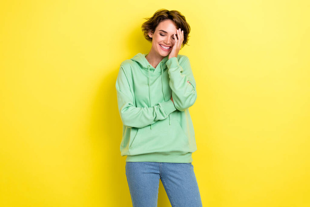 Photo of funky optimistic shy lady wear green clothes arm touch face eyes closed laughing joke isolated on yellow color background. - Photo, image