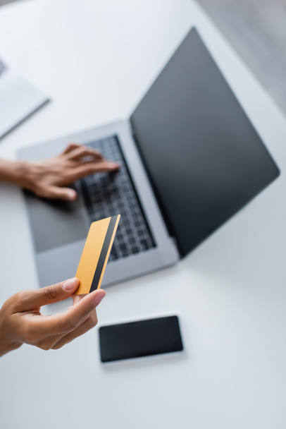 Cropped view of african american woman holding credit card and using laptop with blank screen at home  - Foto, Imagem