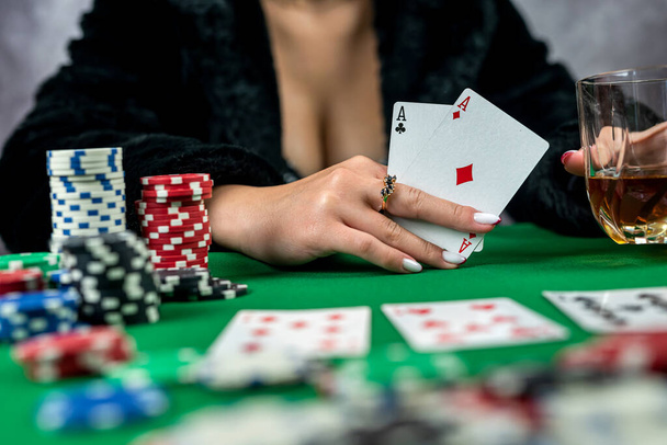 mujer joven está sosteniendo fichas de juego y tarjetas de casino en la mesa en un hermoso vestido. excitación en una mujer. tarjetas en manos femeninas - Foto, imagen