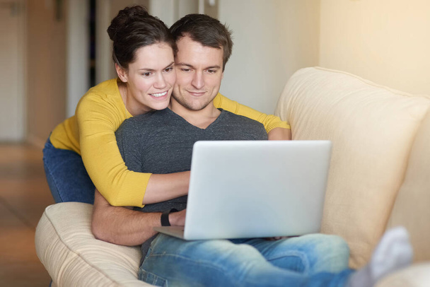 Working on their budget from the comfort of the couch. a loving couple using a laptop together at home - Zdjęcie, obraz