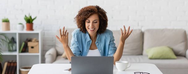 happy african american freelancer gesturing during video call on laptop, banner - Foto, imagen