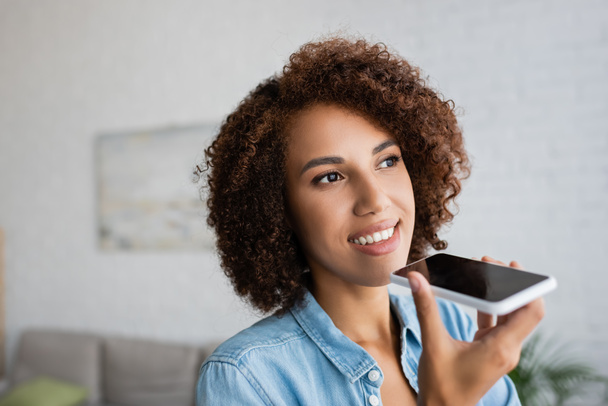 cheerful african american woman with curly hair recording voice message on smartphone  - Photo, Image