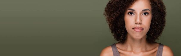portrait of curly african american woman looking at camera isolated on green, banner - Foto, afbeelding