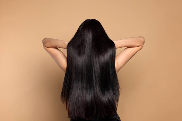 Woman with strong healthy hair on beige background, back view - 写真・画像