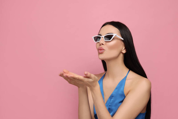 Beautiful young woman in stylish sunglasses blowing kiss on pink background. Space for text - Foto, Bild