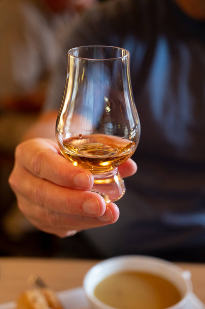 Tasting of single malt scotch whisky in scottish bar in Edinburgh, UK, hand with glass of whisky - Photo, Image