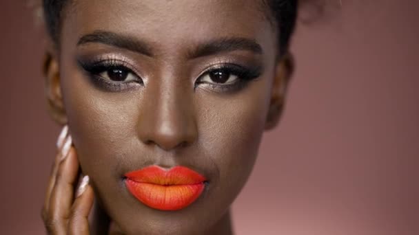 Sensual african american girl with colorful fashion makeup looking at camera while isolated on brown background - Video, Çekim