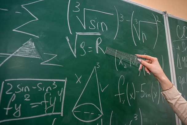 γυναικείο χέρι με κιμωλία και να γράψει μαθηματικό τύπο στον πίνακα. έννοια της εκπαίδευσης. τάξη - Φωτογραφία, εικόνα