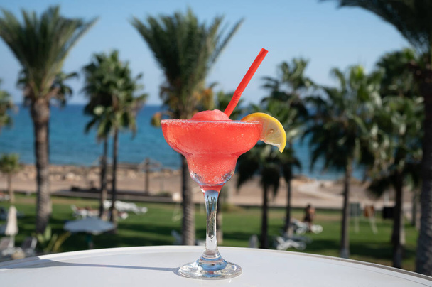 Värikäs jäädytetty vaaleanpunainen Mansikka daiquiri cocktail juoma tarjoillaan lasi ulkona kahvilassa näkymät sininen meri ja palmuja, rentoutua ja loma merellä - Valokuva, kuva