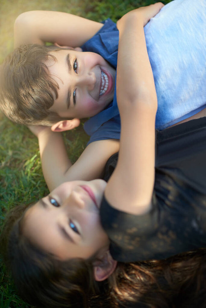 Он мой брат и мой лучший друг. Портрет пары молодых братьев и сестер, обнимающих друг друга, лежащих на траве возле своего дома - Фото, изображение