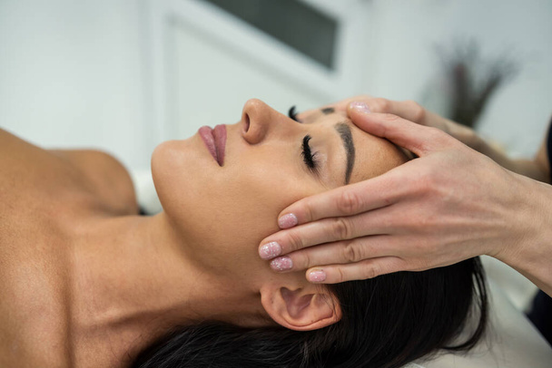 Young woman in beauty spa salon having curative facial massage. Relaxing facial massage - Foto, immagini