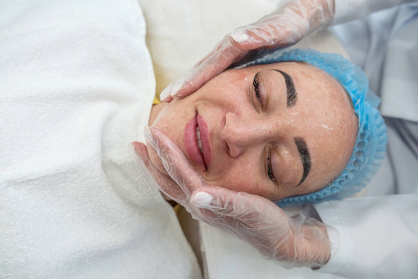 close-up van een schoonheidsspecialiste die procedures uitvoert voor het gezicht van een cliënt in een spa of salon. Een cosmetoloog masseert de patiënt met een facelift. Prachtig. kosmetologische huidprocedures - Foto, afbeelding