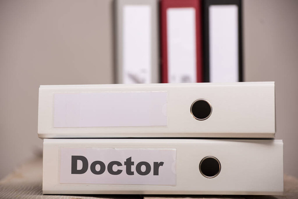 белая папка со знаком DOCTOR, больше папок, стоящих сзади - Фото, изображение