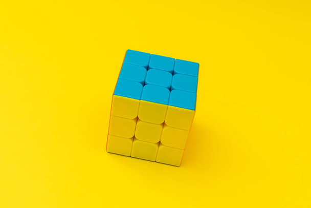 Heldere rubik 's kubus op gele achtergrond, kleurrijke foto - Foto, afbeelding