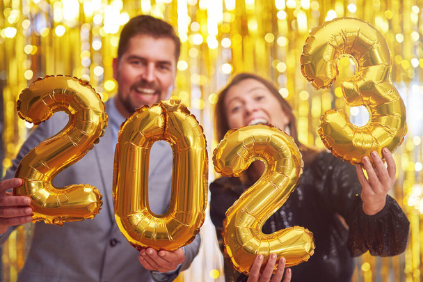 Pareja en la fiesta de fin de año con globos de oro. Foto de alta calidad - Foto, imagen