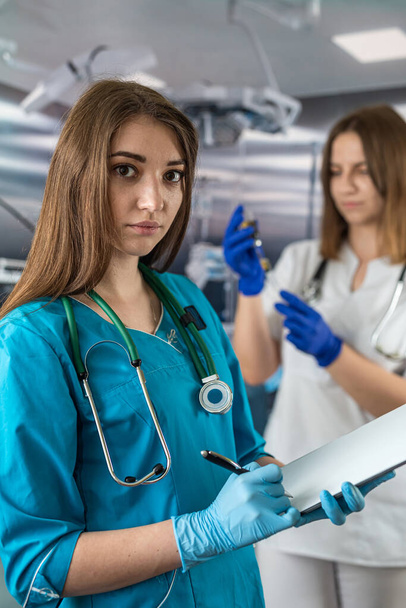 Porträt zweier junger Krankenschwestern in medizinischer Kleidung und lächelnd im Operationssaal. Medizinische Fachkräfte - Foto, Bild
