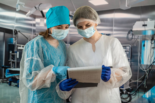 uśmiechnięta pielęgniarka z inną pielęgniarką w korytarzu szpitalnym.pracownicy medyczni podczas pandemii koronawirusowej - Zdjęcie, obraz
