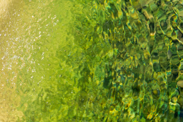 Áramló víz sárga-zöld felülete közelkép háttér - Fotó, kép