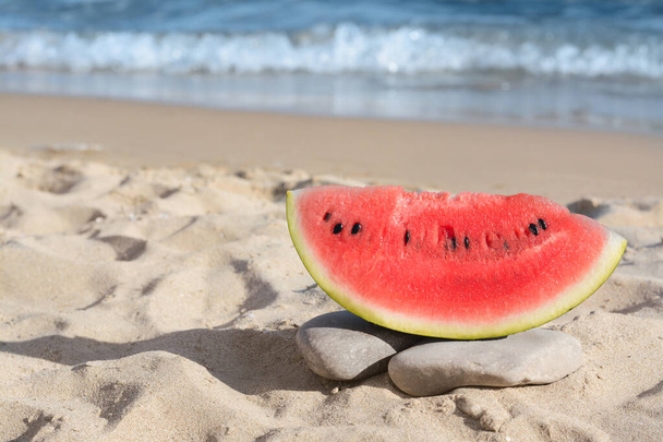 Slice of fresh juicy watermelon near sea, space for text - Zdjęcie, obraz