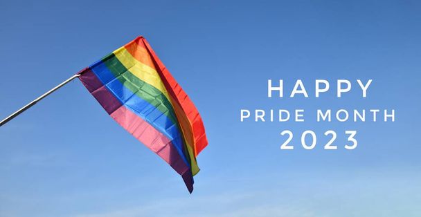 'HAPPY PRiDE MONTH 2023' on bluesky and rainbow flag background, concept for lgbtq + celebrations in pride month, czerwiec, 2023. - Zdjęcie, obraz