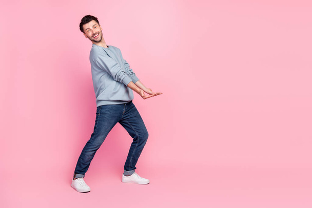 Full body photo of nice young man carry hold empty space banner toothy smiling wear stylish blue outfit isolated on pink color background. - Фото, зображення