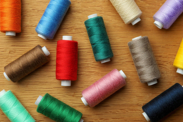 Many colorful sewing threads on wooden table, flat lay - Foto, imagen
