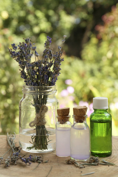 Beautiful lavender flowers and bottles of essential oil on wooden stump - Foto, immagini