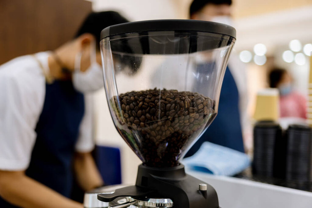 Coffee beans in electric coffee grinder. Freshly roasted coffee beans in  Coffee Grinder machine. Coffee beans in caf. - Foto, immagini