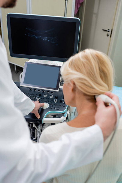 verschwommener Arzt bedient Ultraschallgerät bei Diagnose von Frau in Klinik - Foto, Bild