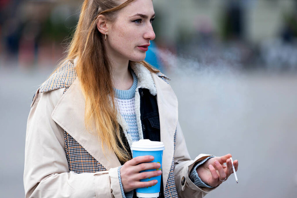 real young woman smoking outdoors, selective focus. - Foto, afbeelding