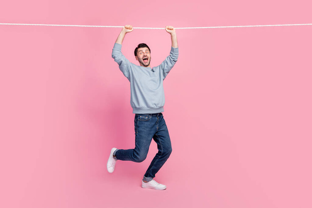 Full length photo of carefree guy hang on string playing game isolated pastel color background. - Foto, Imagen