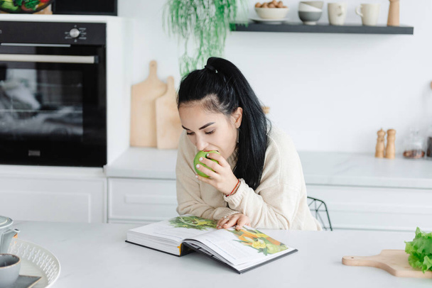 Alimentación Saludable. Una mujer joven come un montón de verduras. Auto-cuidado. Mujer leyendo una revista sobre dieta y alimentación saludable. - Foto, imagen