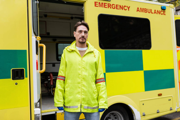 Paramedic in latex gloves standing near ambulance car outdoors  - Foto, imagen