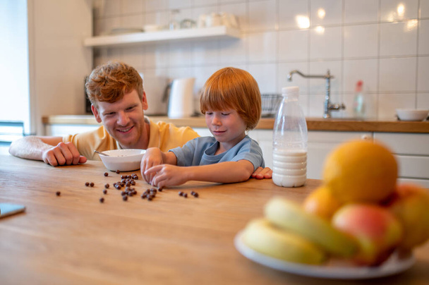 Playing before beakfast. Dad and son spending time together in the kitchen before breakfast - Fotoğraf, Görsel