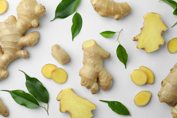 Fresh ginger with green leaves on white background, flat lay - Foto, afbeelding