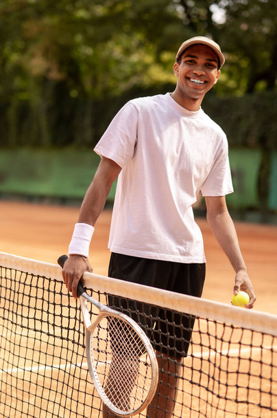 Tennis player. Young man in white tshirt with a tennis racket in hands - Foto, afbeelding
