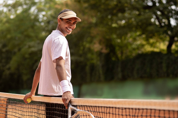 Workout. Young man in sun visor at the tennis courts - Fotó, kép