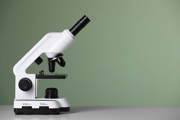 Modern microscope on table against green background. Space for text - Фото, изображение