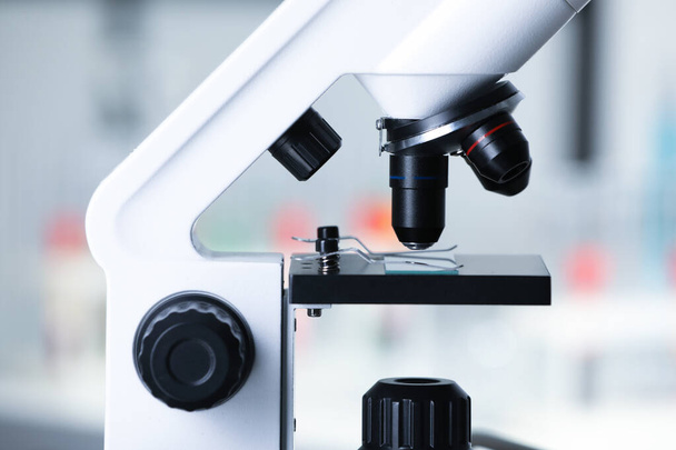 Modern medical microscope with glass slide on blurred background, closeup - Foto, Imagem