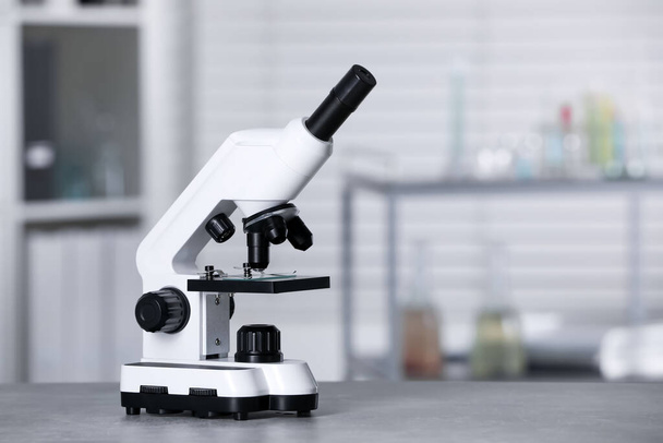 Modern medical microscope on grey table in laboratory, space for text - Fotó, kép