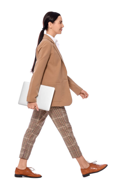 Young businesswoman with laptop walking on white background - Zdjęcie, obraz