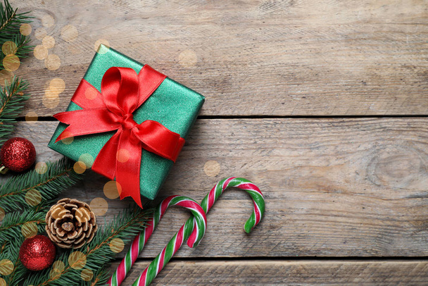 Ajándék doboz, cukornád, fenyőfa ágak és karácsonyi dekoráció fa asztalon, lapos fektetés. A szöveg helye - Fotó, kép