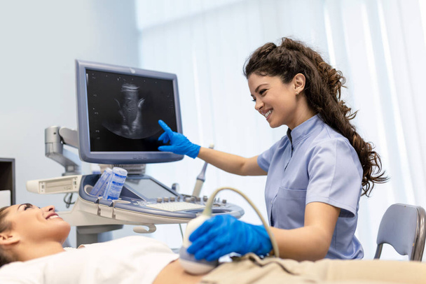 Ultrazvuková diagnostika žaludku na břiše k ženě na klinice, detailní záběr. Doktor provádí ultrazvukový senzor na břiše pacientky a dívá se na obraz na obrazovce. Diagnóza vnitřních orgánů. - Fotografie, Obrázek