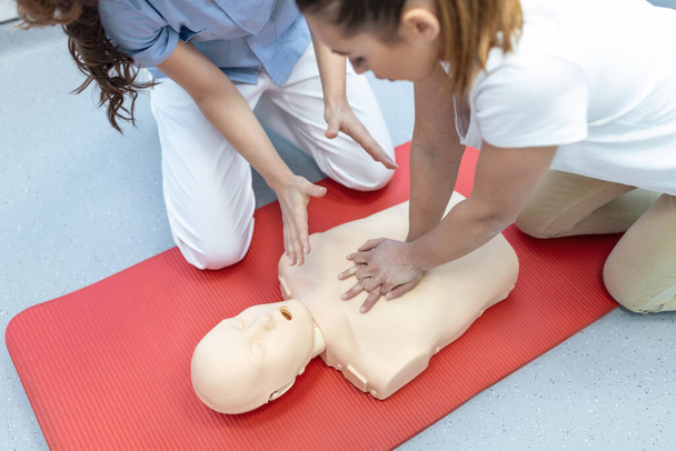 Demonstrace CPR (Kardiopulmonální resuscitace) trénink lékařské procedury na CPR panenku ve třídě. Lékař a sestra studenti se učí, jak zachránit pacienta.První pomoc pro bezpečnou životní koncepci. - Fotografie, Obrázek