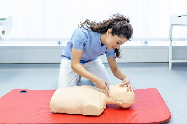 kobieta praktykująca technikę resuscytacji na manekinie podczas szkolenia pierwszej pomocy. Szkolenie w zakresie pierwszej pomocy - resuscytacja mięśnia sercowego. Kurs pierwszej pomocy na manekinie pierwszej pomocy. - Zdjęcie, obraz