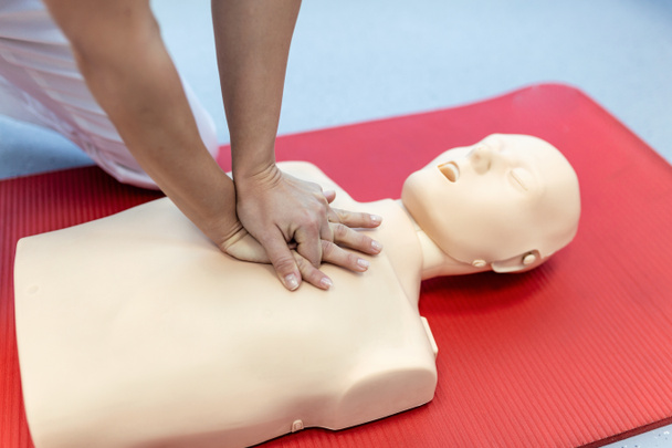 Újraélesztő tréning orvosi eljárás - A mellkas kompressziójának bemutatása az osztályban lévő CPR babán. Elsősegély-képzés - Kardiopulmonális újraélesztés. Elsősegély tanfolyam újraélesztő próbabábun. - Fotó, kép