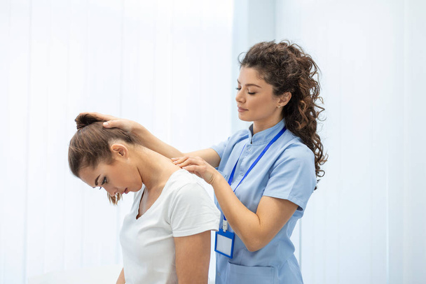 Licensed chiropractor or manual therapist doing neck stretch massage to relaxed female patient in clinic office. Young woman with whiplash or rheumatological problem getting professional doctor's help - Photo, Image