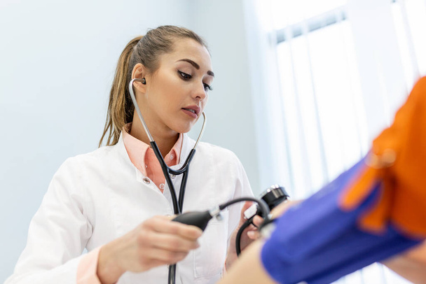 Lékař pomocí sfygmomanometru se stetoskopem kontrolu krevního tlaku na pacienta v nemocnici. - Fotografie, Obrázek